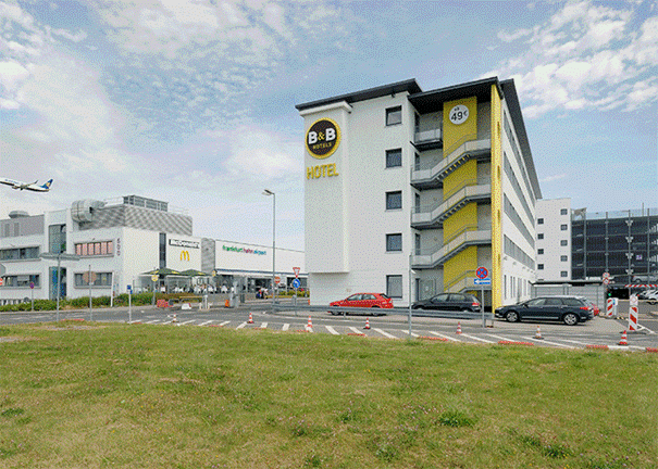 Hotelgebäude, Parkhaus, Autos, Grünfläche und Flugzeug