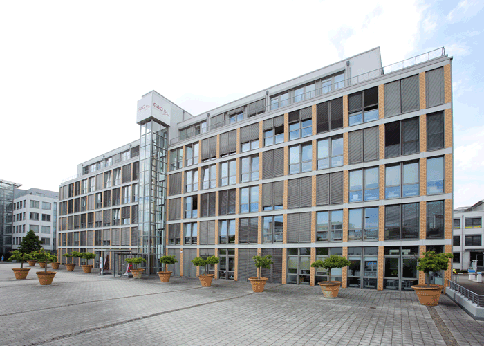 geplasterte wenig befahrene Straße, Pflanzkübel, blauer Himmer und Bürogebäude