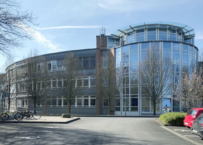 Bürogebäude mit Glasfassade PKW und Fahrrad Parkplätzen